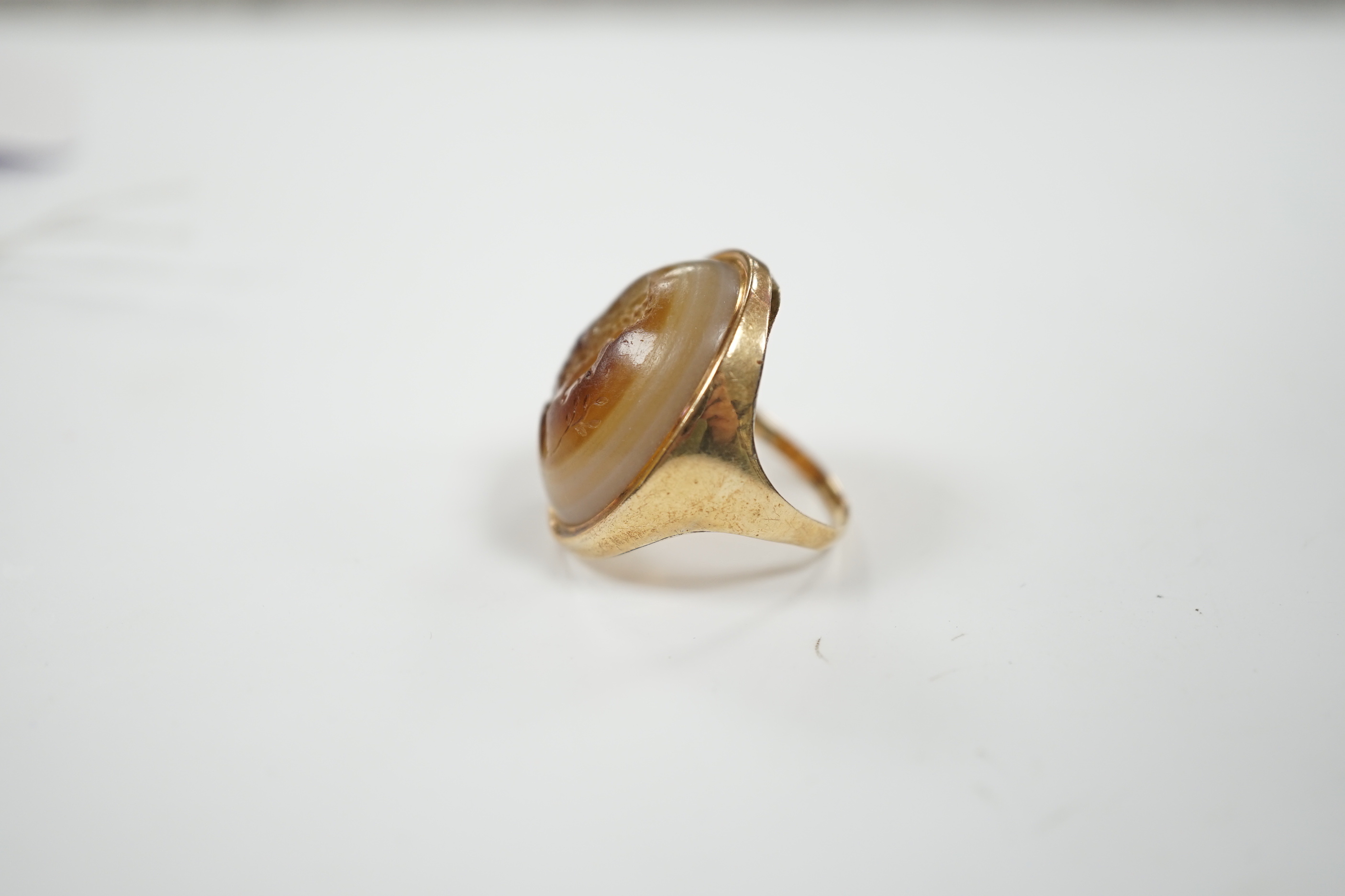 An early 20th century yellow metal and banded agate intaglio ring, carved with the head of a gentleman to sinister, size L, gross weight 8.1 grams.